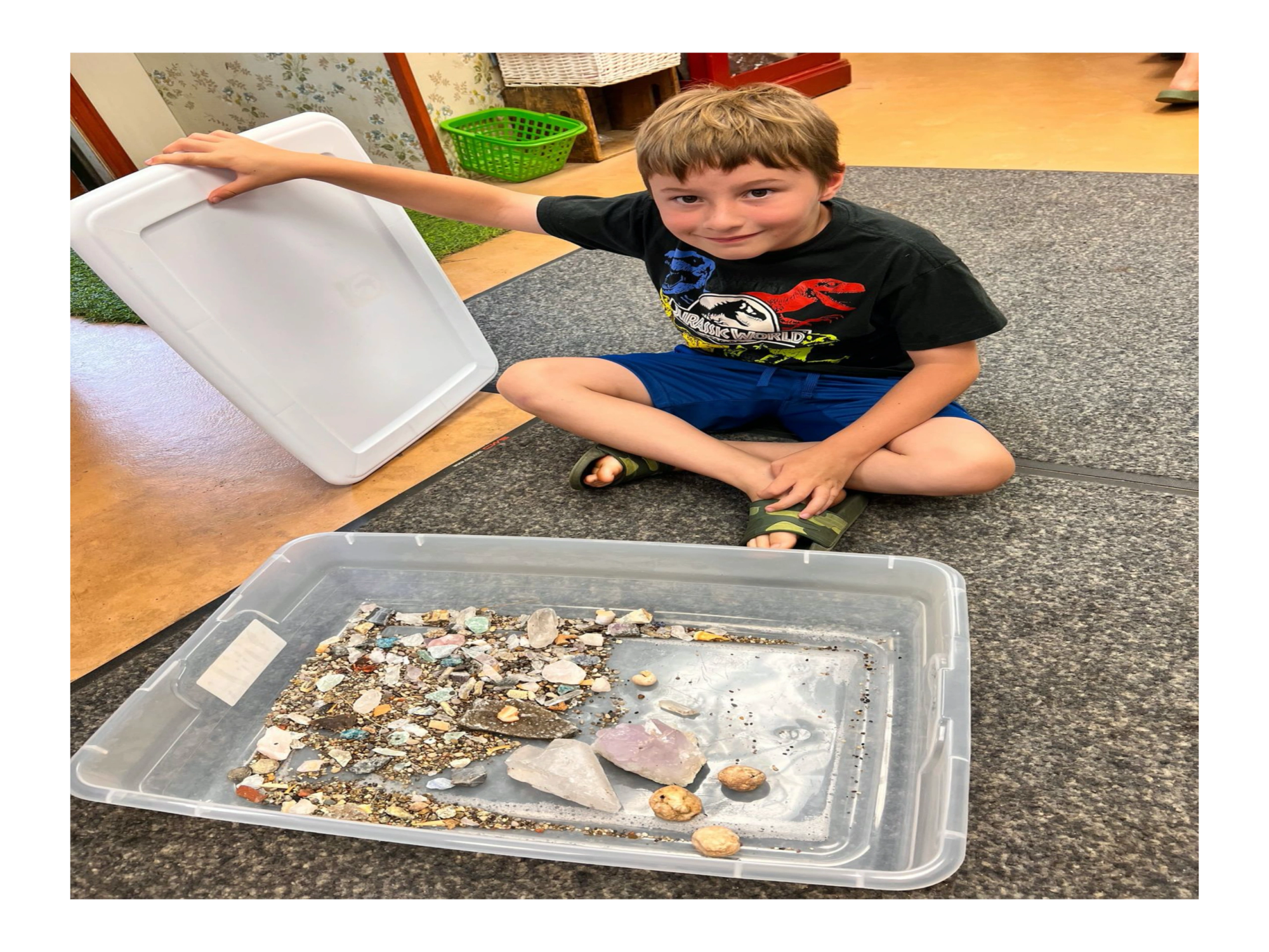A child sitting with a tray of screened stones and gems