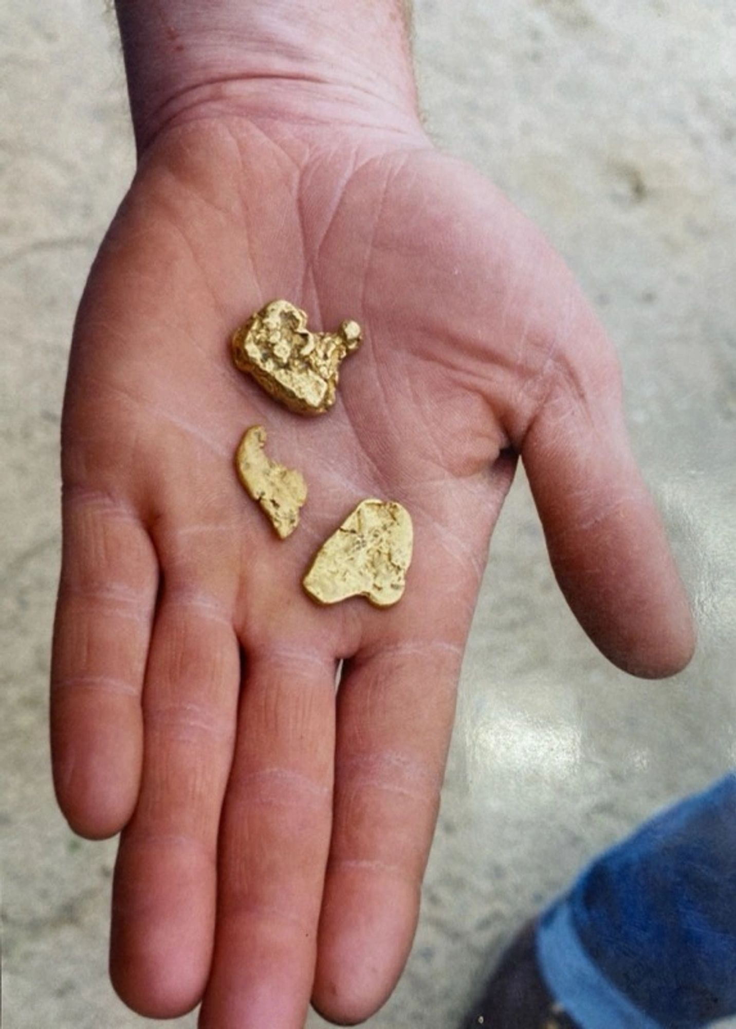 Several gold nuggets resting in an open palm