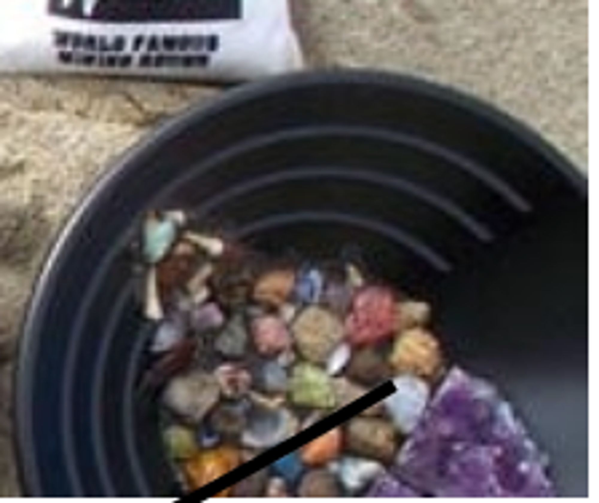 A tin full of colorful tumbled gemstones and crystals