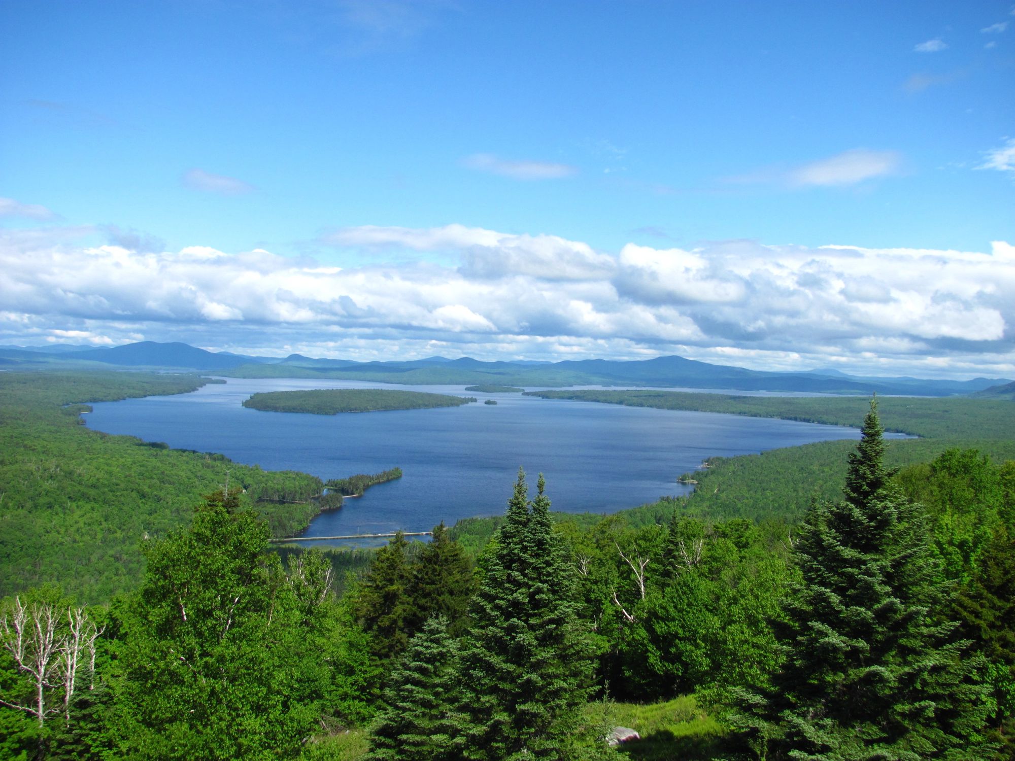 A long view over forested ridges and a lake in the Western Maine mountains